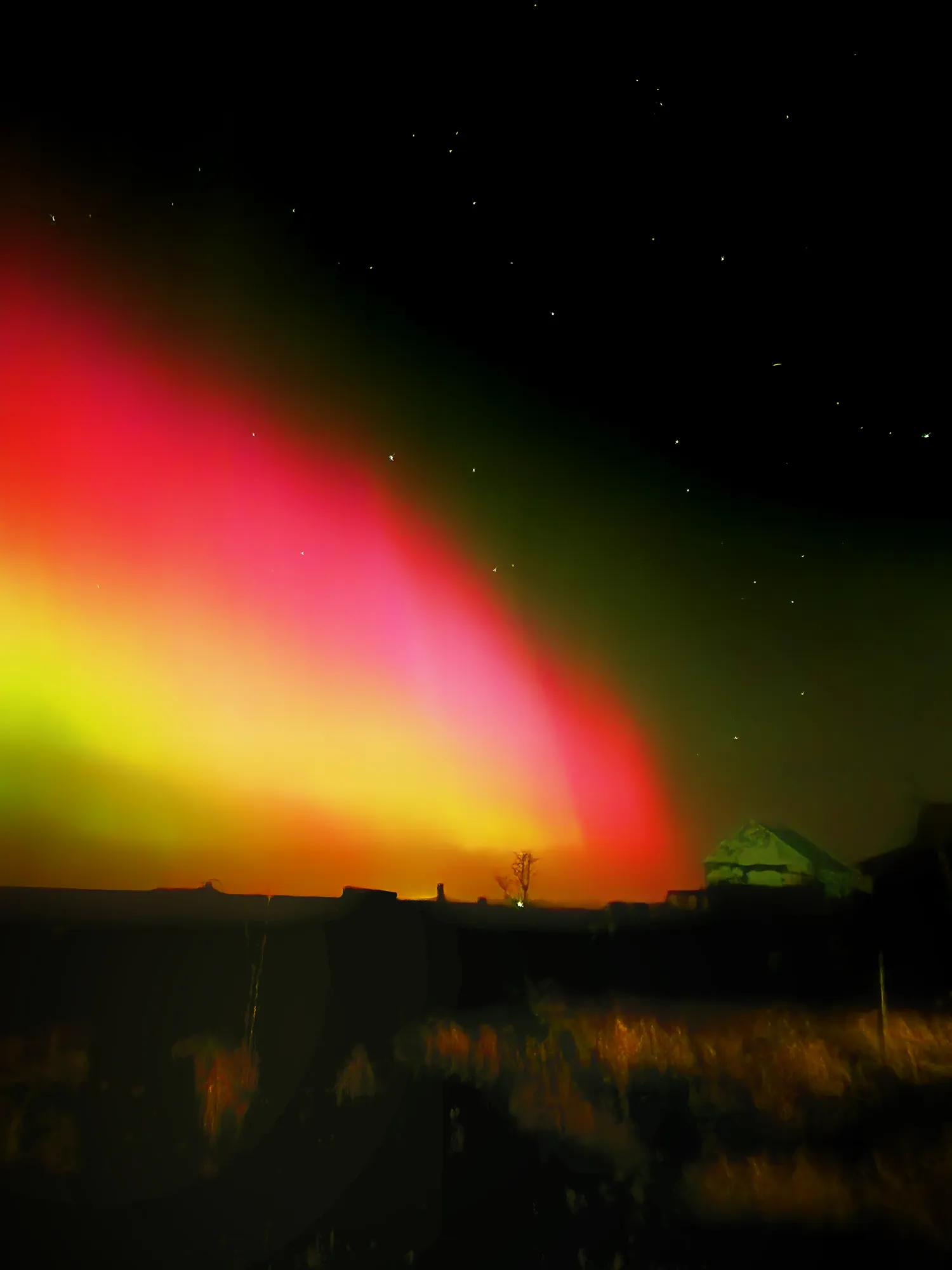 Rare red and yellow aurora low over the horizon at Ormskot farm, South Iceland