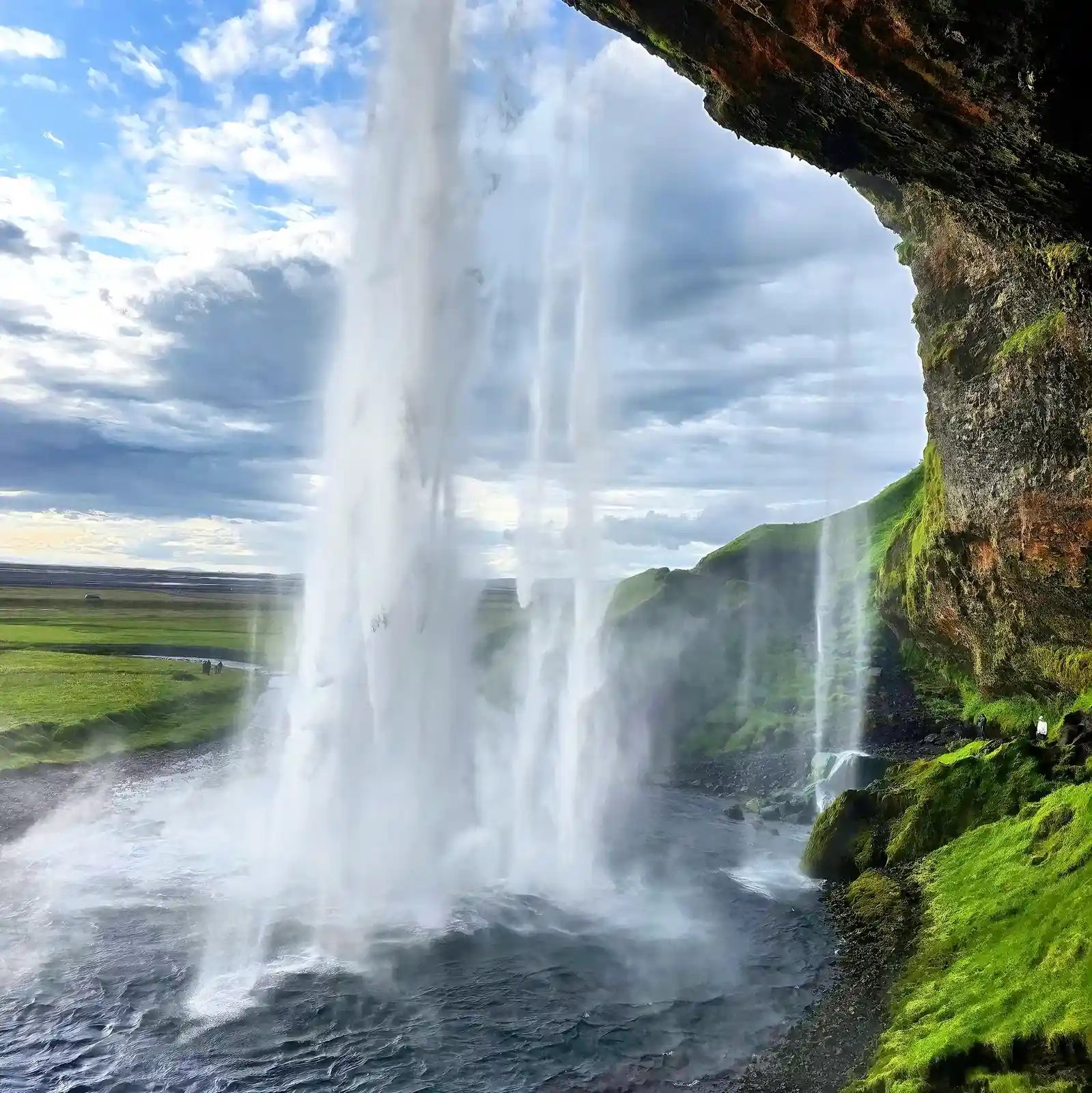 Walking behind Seljalandsfoss waterfall misty path South Iceland