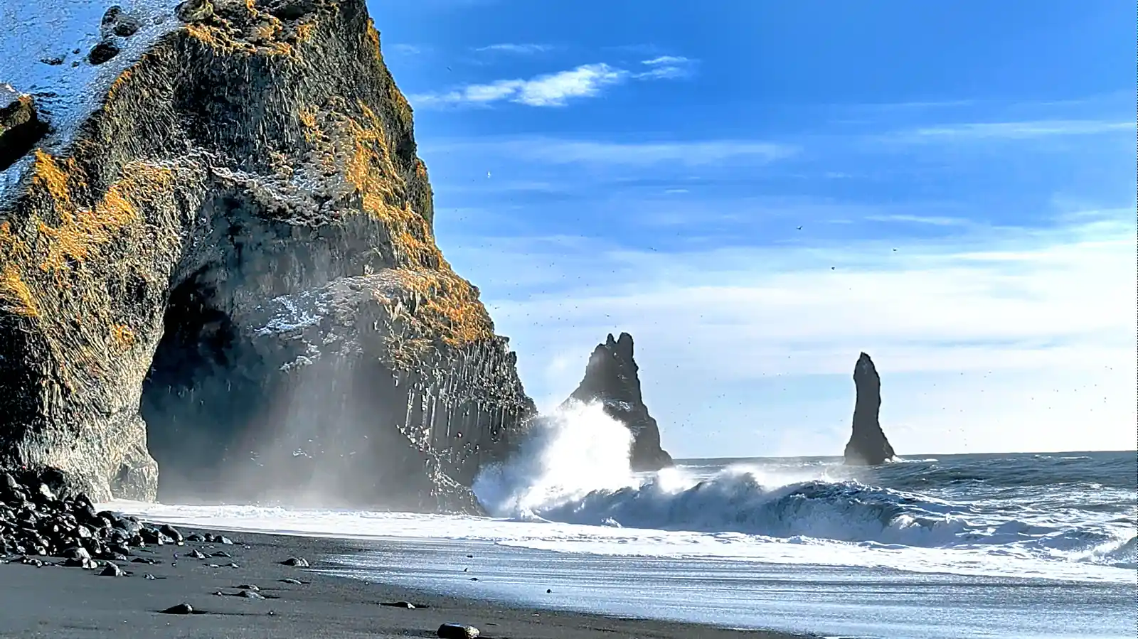 Reynisfjara black sand beach with Reynisdrangar sea stacks and crashing waves Iceland