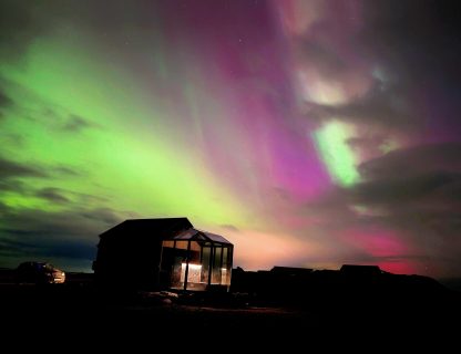 purple and green northern lights over glass igloo south Iceland